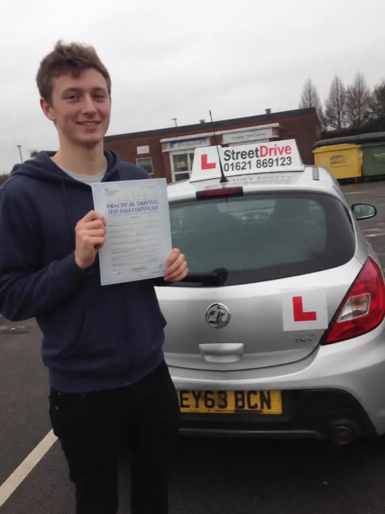 Freddie holding their driving test pass certificate in Liverpool