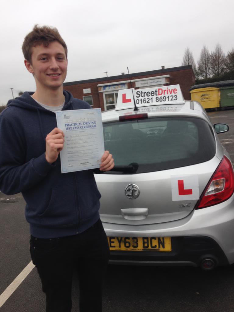 Freddie holding their driving test pass certificate in Liverpool