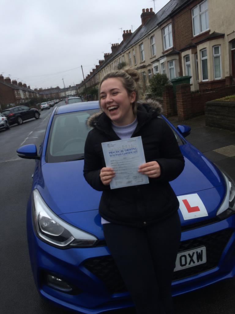 Rebecca holding their driving test pass certificate in East London