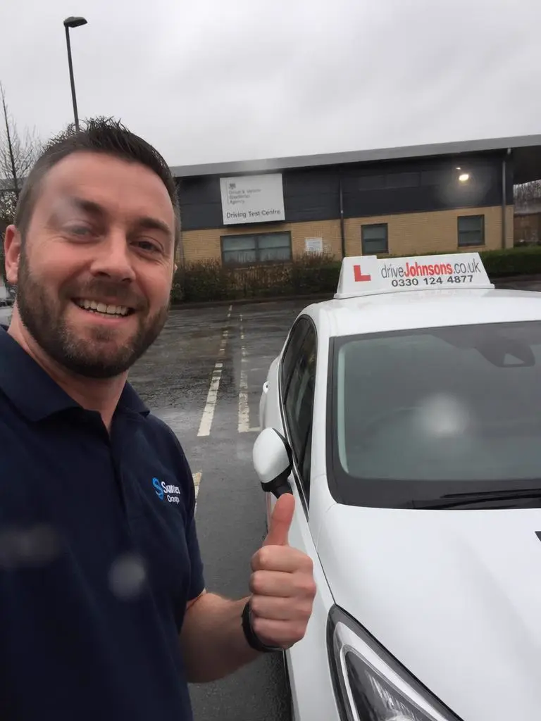 Marek holding their driving test pass certificate in Leeds
