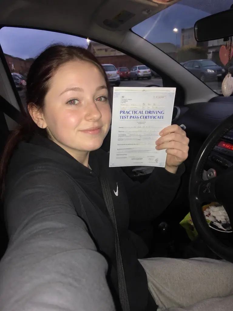 Aimee holding their driving test pass certificate in Bristol