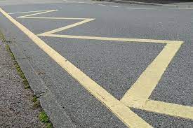 Illustration for the theory test question: This school's exterior road is designated with yellow zigzag lines. What are the meanings of these lines?